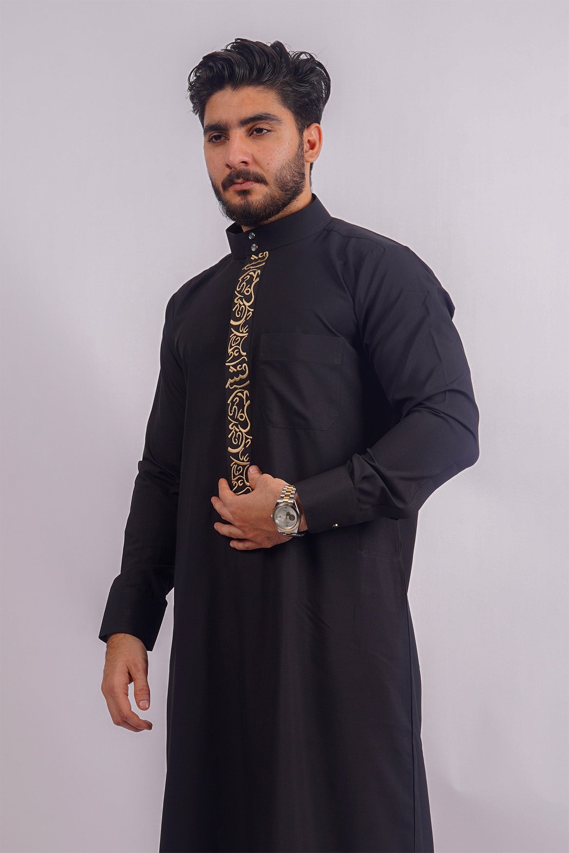Aamsah's Black Saudi Thobe: Intricate golden embroidery on a sophisticated black backdrop, tailored for elegance and Muslim ceremonies.