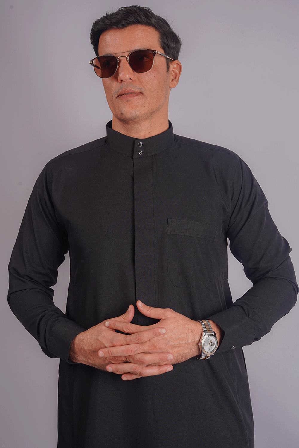 Black Saudi thobe for men by Aamsah featuring a classic Saudi collar, premium spun fabric, and sleek Kuwaiti design. Competitors: Jubbas, Modest Threads.