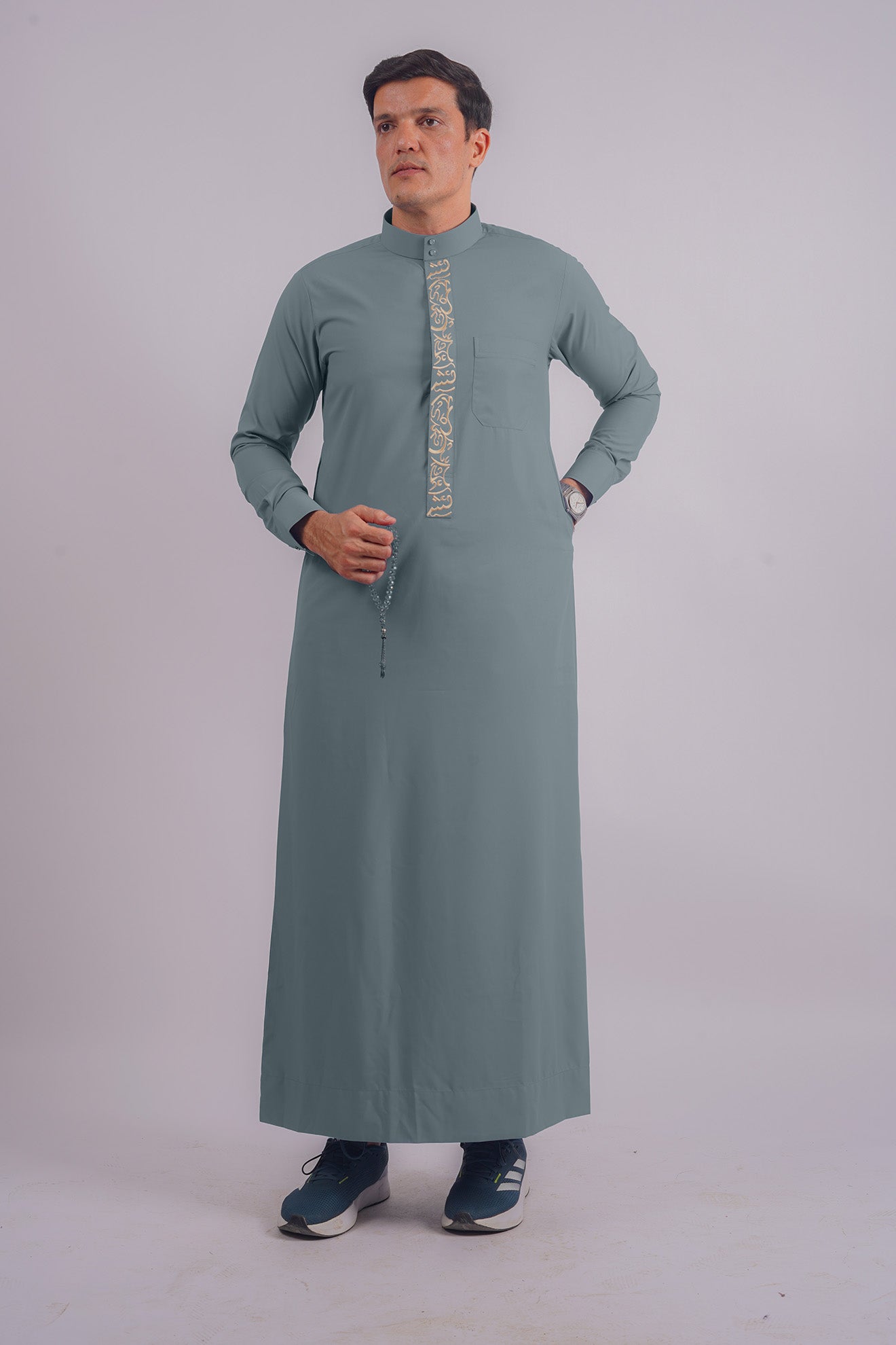 Aamsah's Dusty Blue Saudi Thobe with Golden Embroidery, blending modern style with classic Saudi elements, perfect for weddings and religious gatherings.