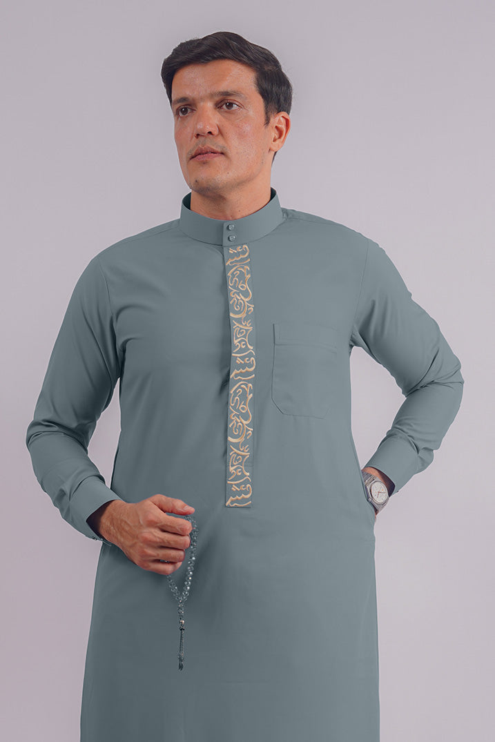 Elegant Dusty Blue Saudi Thobe by Aamsah, featuring intricate golden embroidery inspired by traditional Saudi craftsmanship, ideal for special occasions.